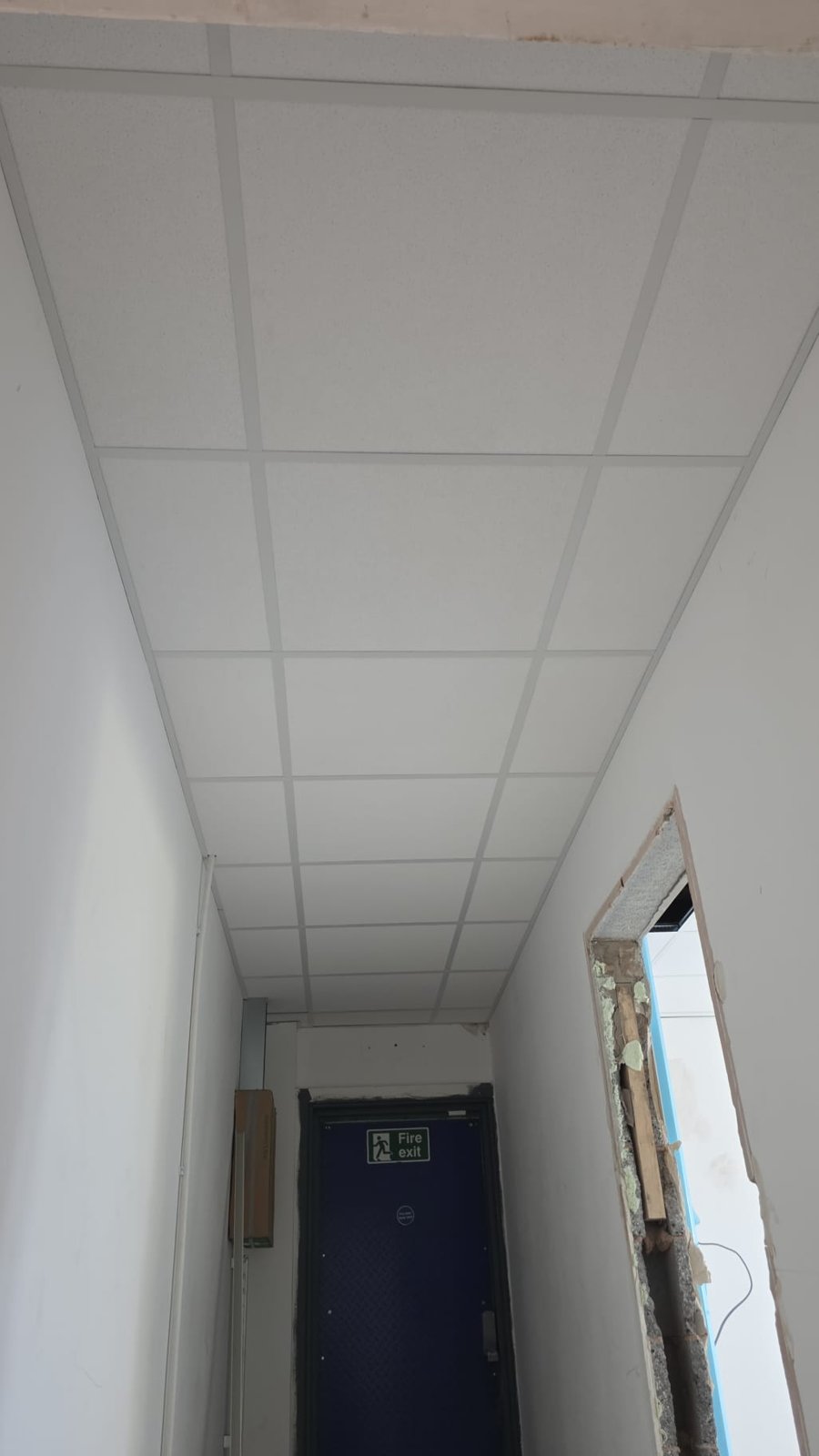 Suspended ceiling tiles fitted along an interior corridor